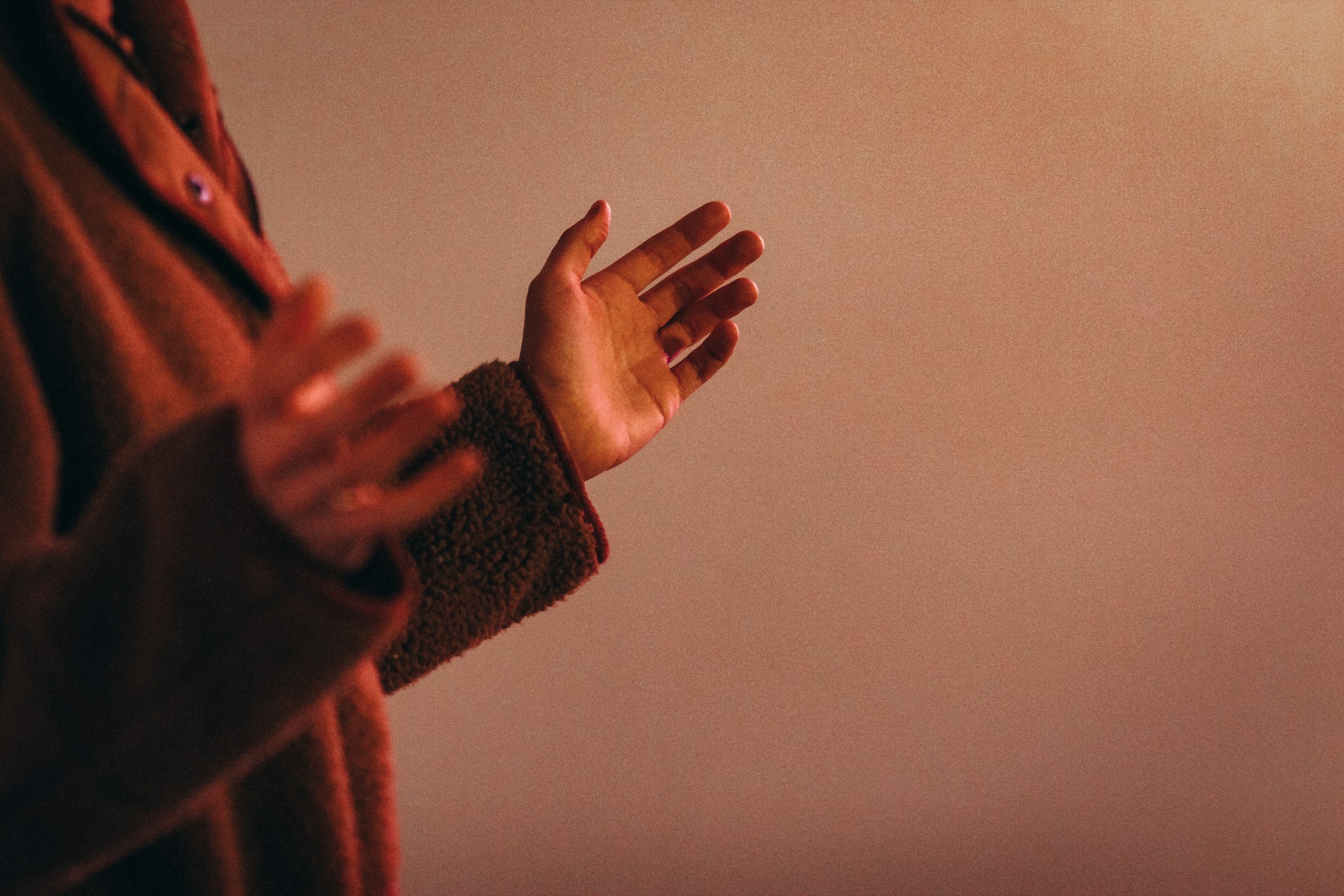 Open hands raised in prayer in warm light